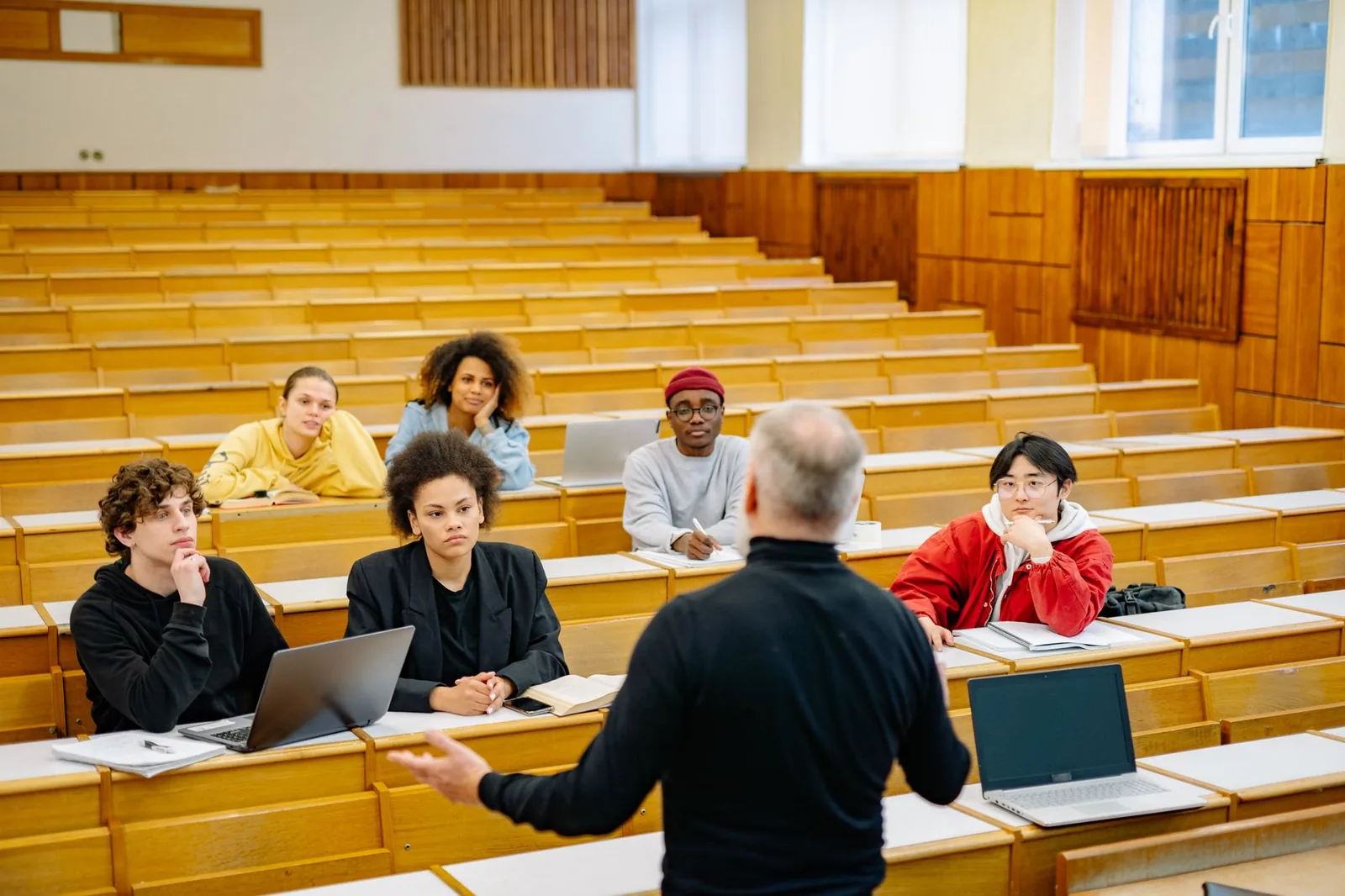 Étudiants suivant un cours magistral dans un amphithéâtre universitaire en bois