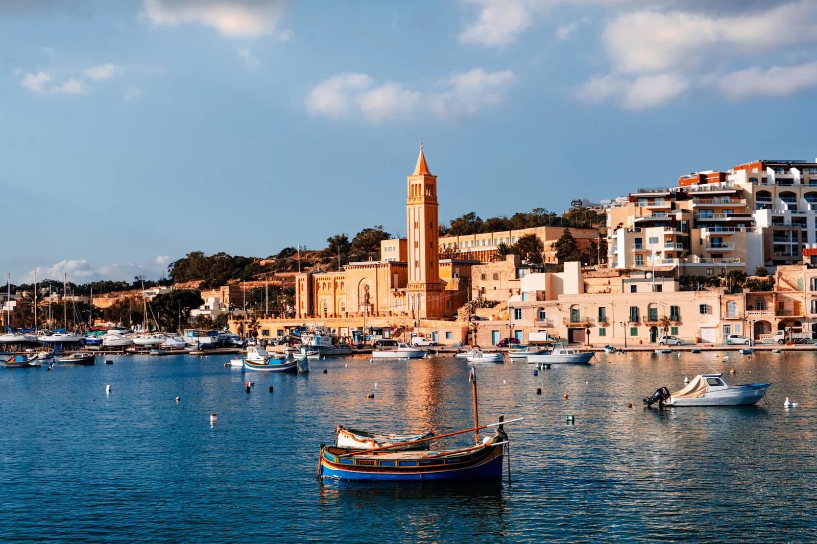 La baie de Marsaskala avec son clocher, des luzzu amarrés et les immeubles du front de mer