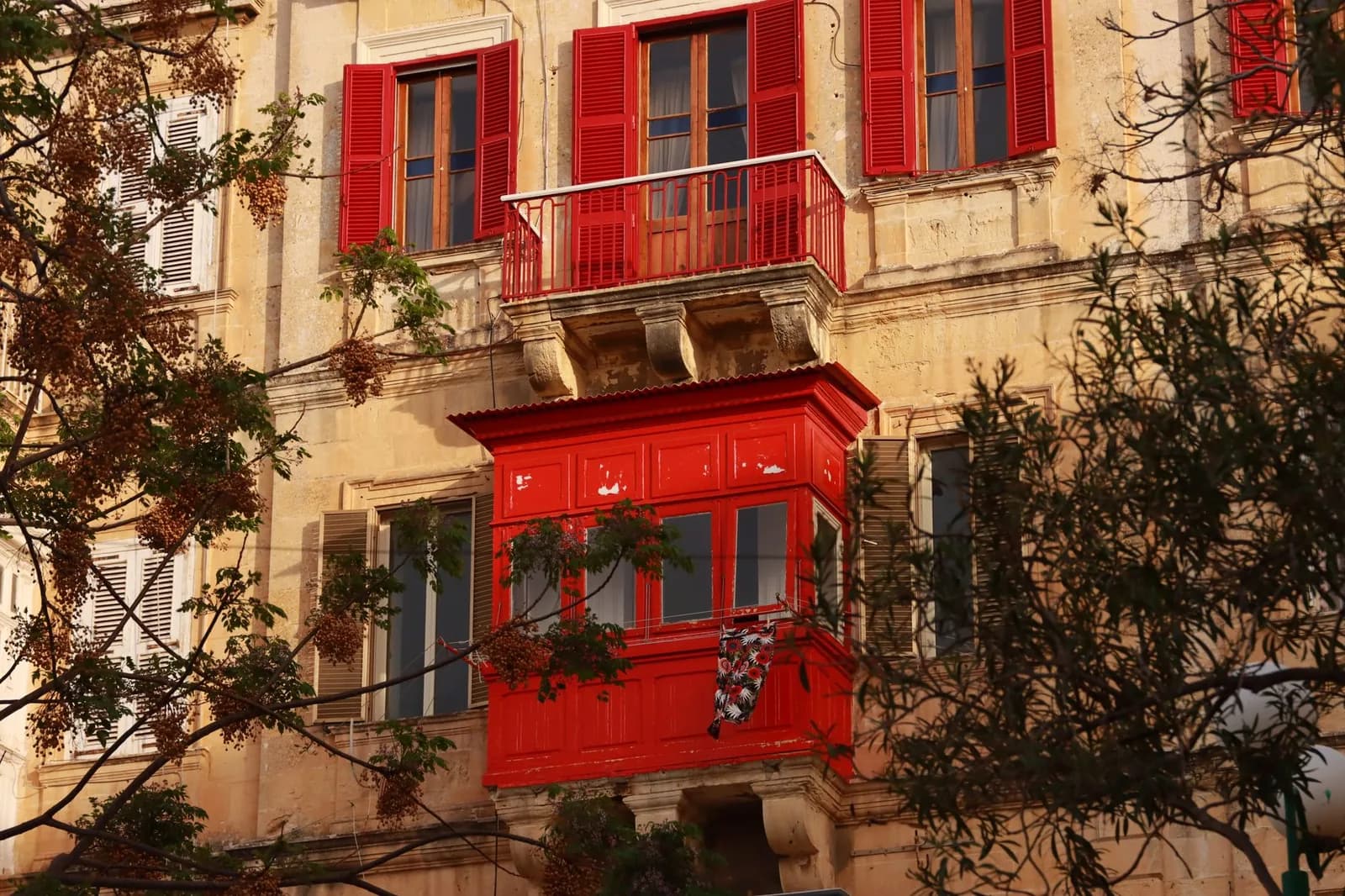 Façade en pierre de La Valette avec balcons fermés rouges typiquement maltais