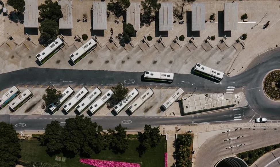 Vue aérienne du terminus de bus de La Valette, à Malte, avec des bus blancs et verts garés en épis le long des quais abrités