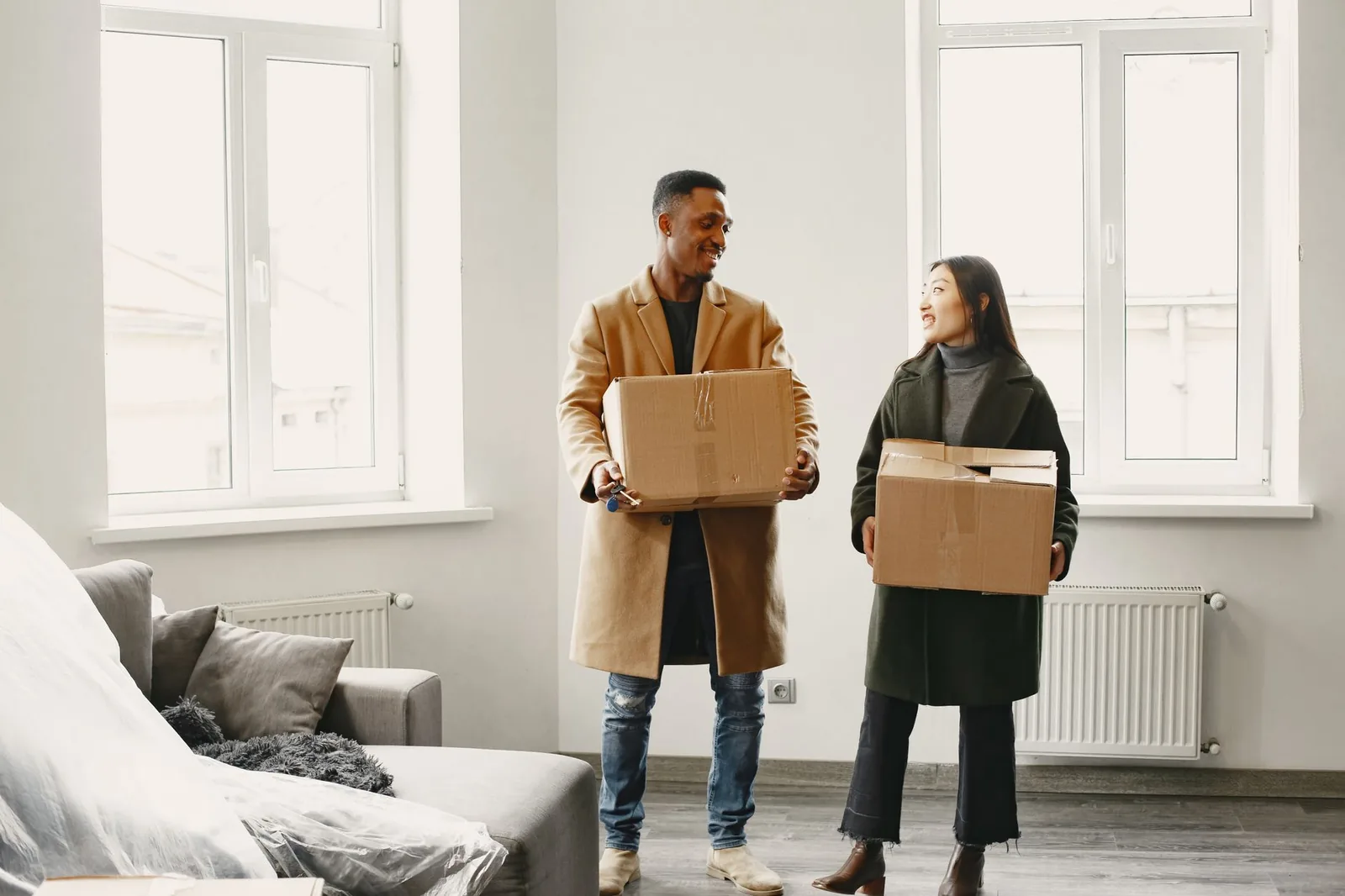 Couple portant des cartons de déménagement dans un appartement lumineux le jour de l'emménagement