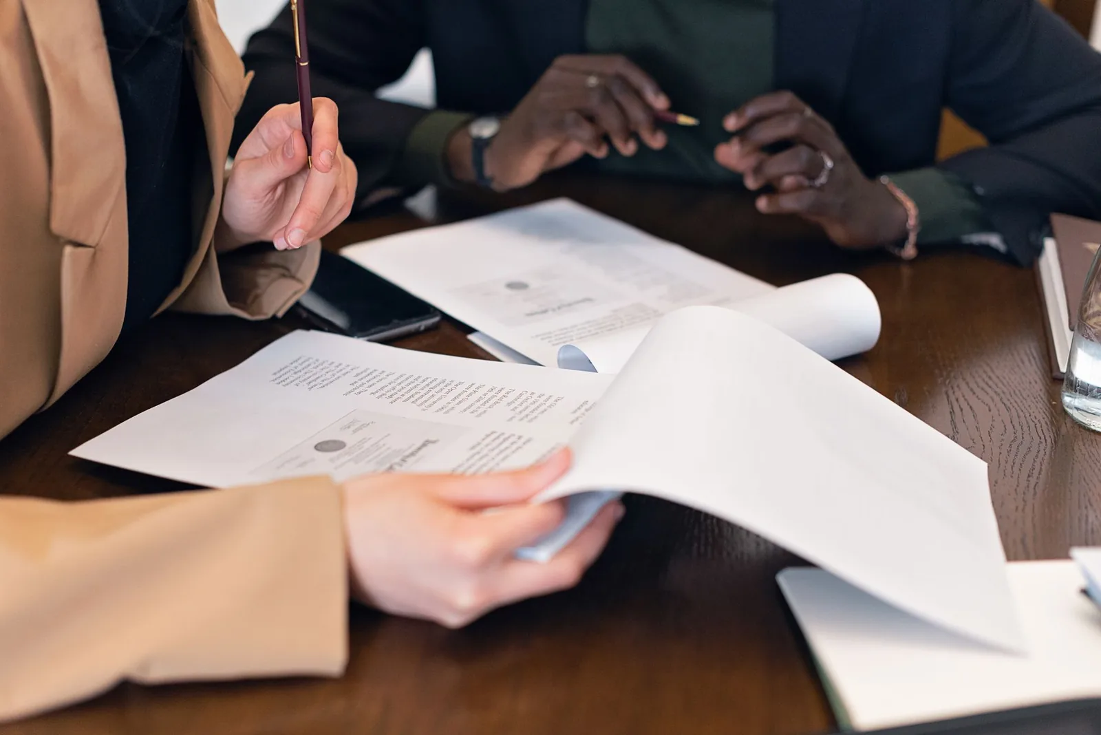 Deux personnes comparant des contrats papier posés côte à côte sur une table