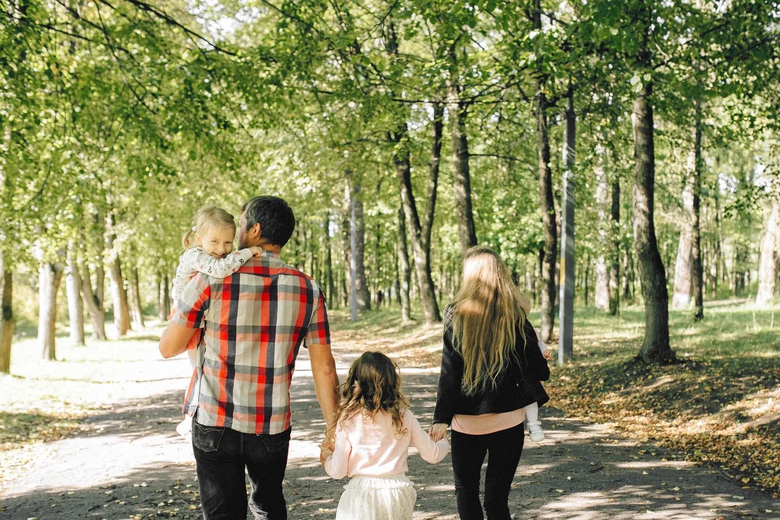 Famille avec deux enfants en promenade sur un chemin ombragé