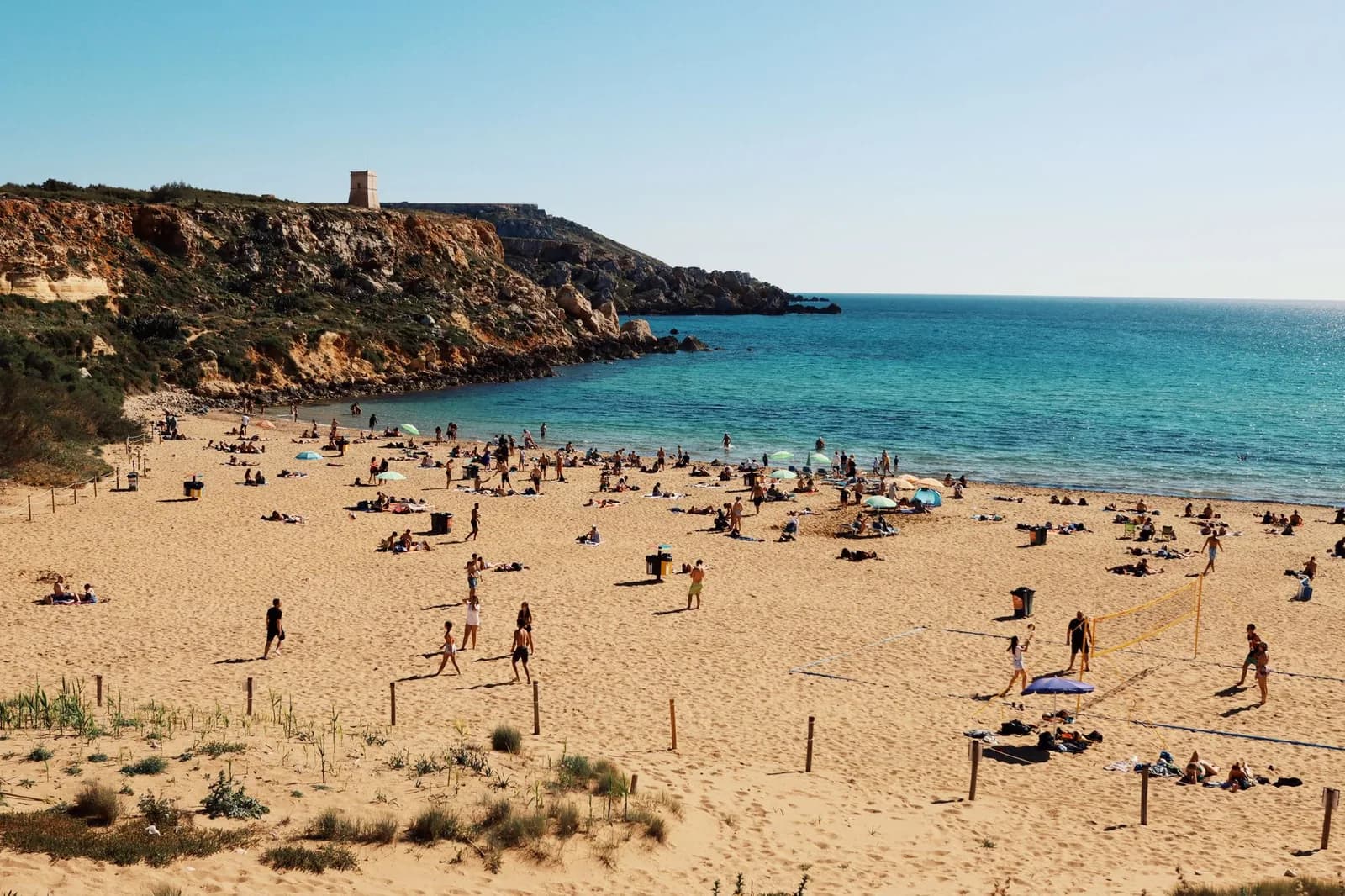 Plage de sable doré de Golden Bay, falaise et tour de guet dominant une mer turquoise, nord-ouest de Malte