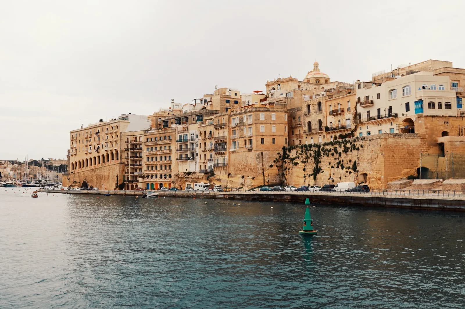 Immeubles en pierre calcaire et balcons maltais alignés au bord de l'eau, à Senglea (Malte)