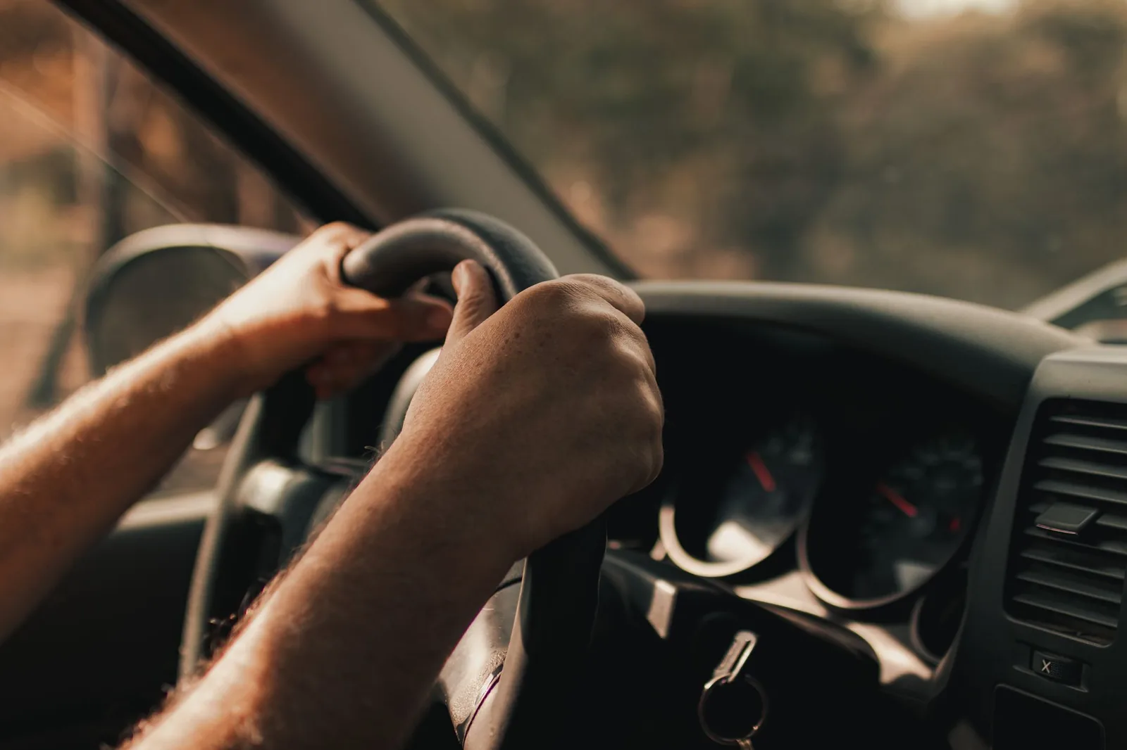 Mains d'un conducteur sur le volant d'une voiture sur une route de campagne