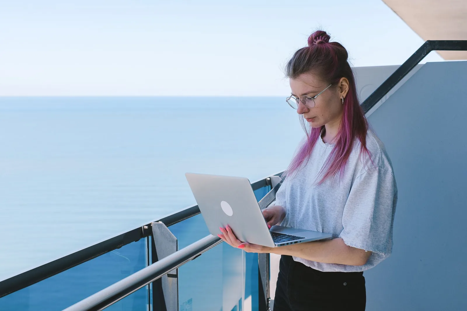 Travailleuse à distance avec son ordinateur portable sur un balcon face à la mer