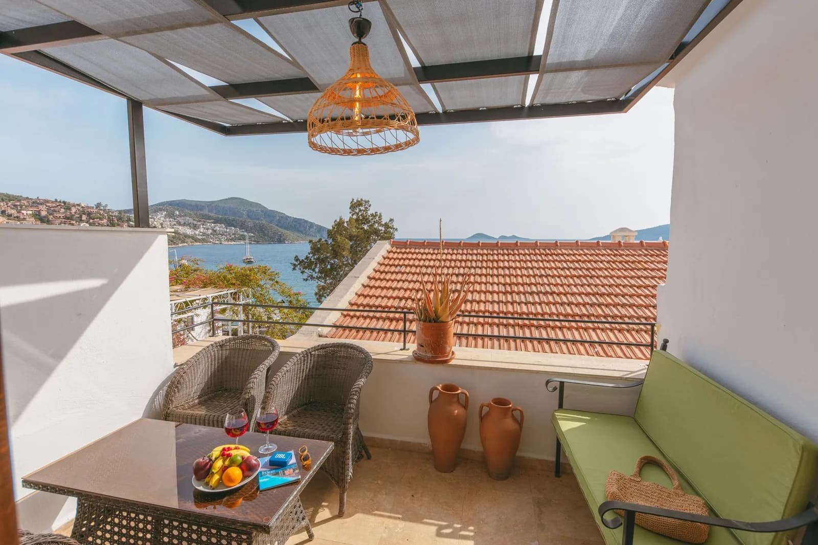 Terrasse ombragée d'une chambre d'hôtel donnant sur une baie méditerranéenne