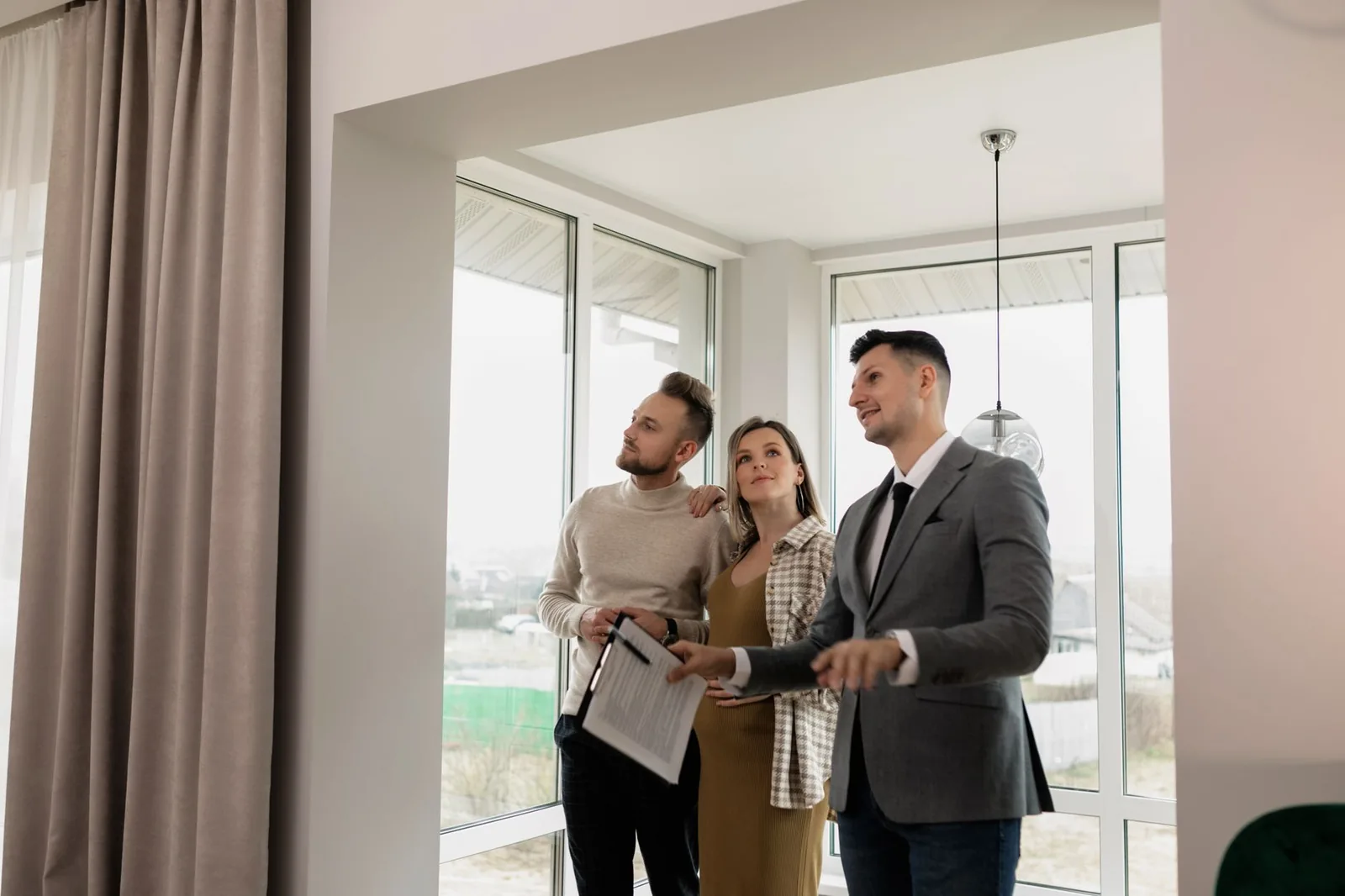 Agent immobilier faisant visiter un appartement lumineux à un couple