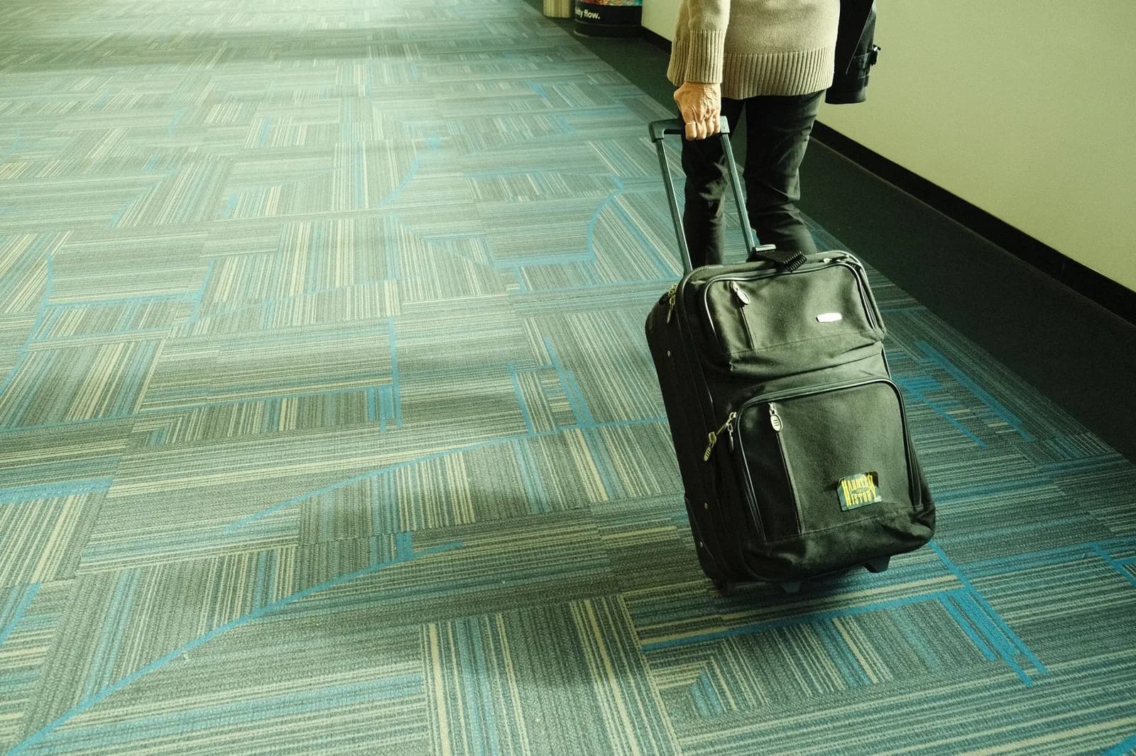Voyageur tirant une valise cabine à roulettes dans un couloir d'aéroport