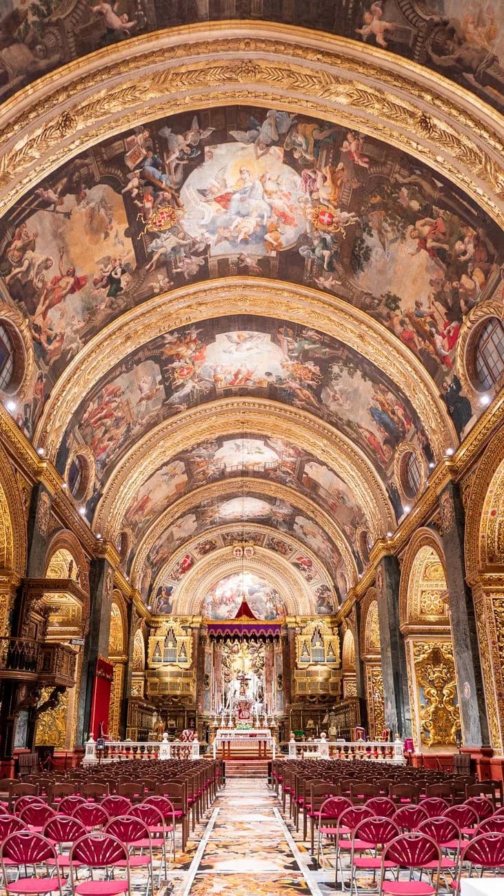 Nef baroque dorée de la co-cathédrale Saint-Jean à La Valette, avec ses fresques et ses rangées de chaises rouges