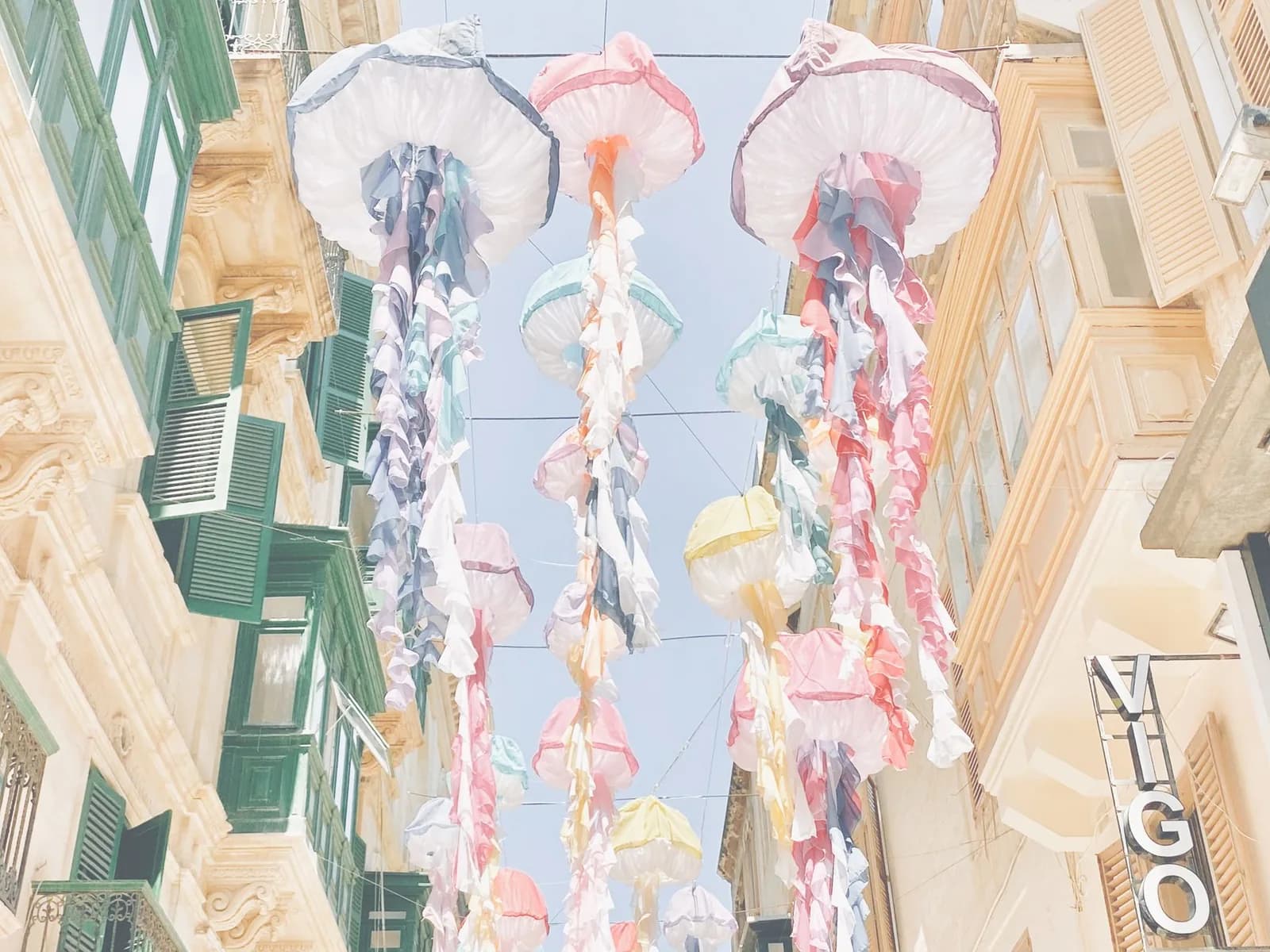 Décorations colorées suspendues au-dessus d'une rue bordée de balcons maltais à La Valette pendant les festivités