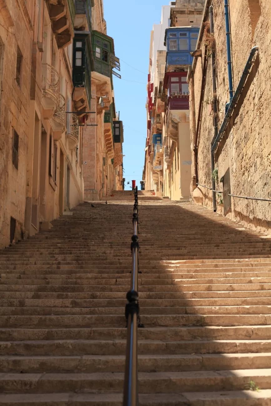 Rue en escalier de pierre à La Valette à Malte, bordée de balcons maltais colorés
