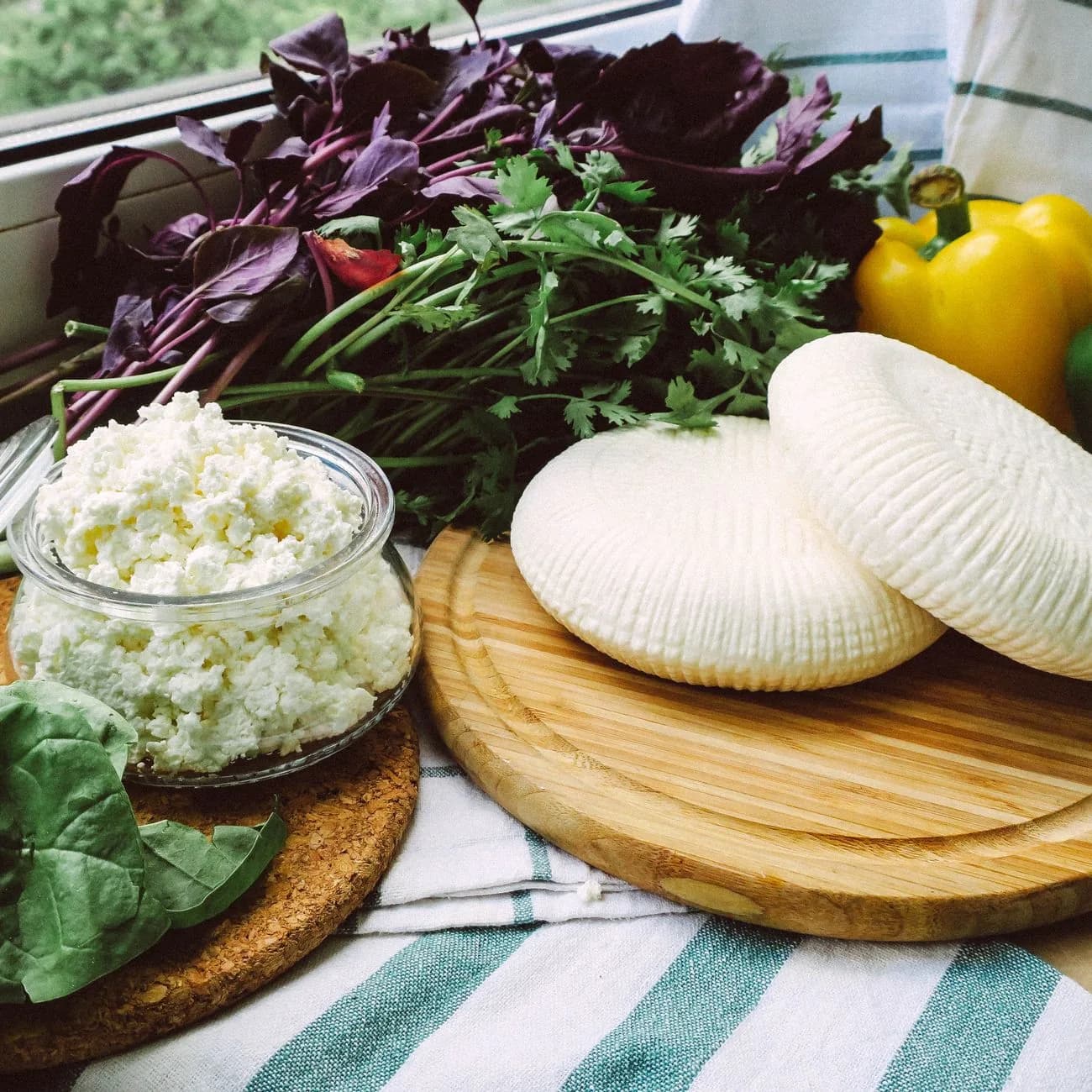Petits fromages ronds de brebis frais posés sur une planche, comme les ġbejniet produits à Gozo