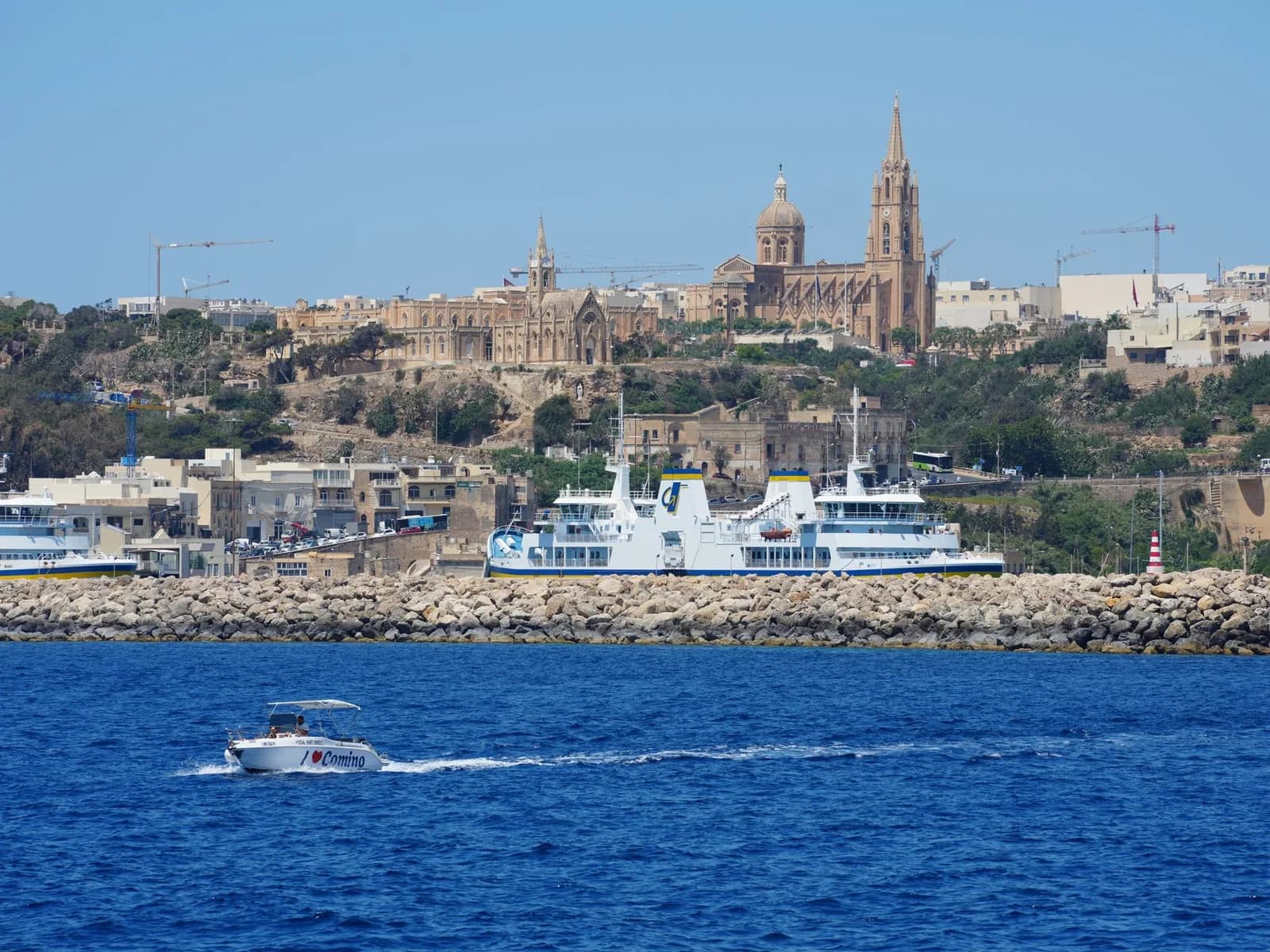 Port de Mġarr à Gozo avec un ferry blanc, et l'église de Għajnsielem sur la colline