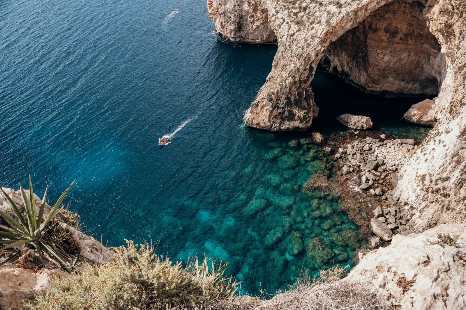 L'arche naturelle de la Grotte Bleue à Malte vue depuis la falaise, avec un bateau sur l'eau turquoise