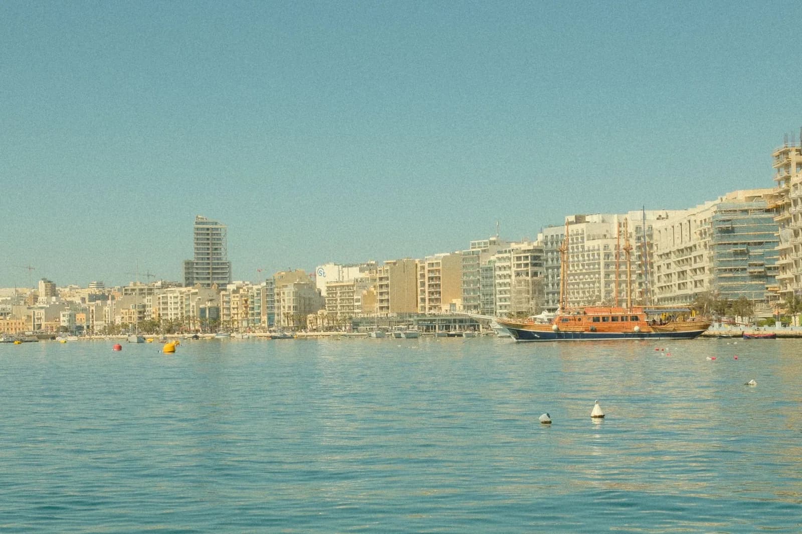 Front de mer de Sliema à Malte bordé d'hôtels et d'immeubles modernes, avec un bateau de croisière amarré