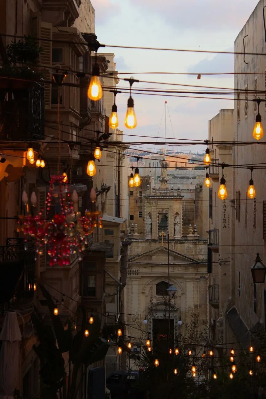 Rue de La Valette au crépuscule, avec des guirlandes d'ampoules suspendues et une décoration rouge de fêtes sur un balcon