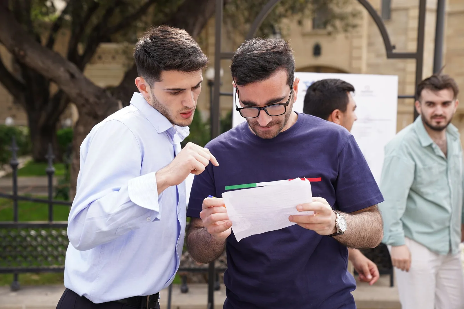 Deux jeunes étudiants consultant un document devant un bâtiment en pierre calcaire à Malte