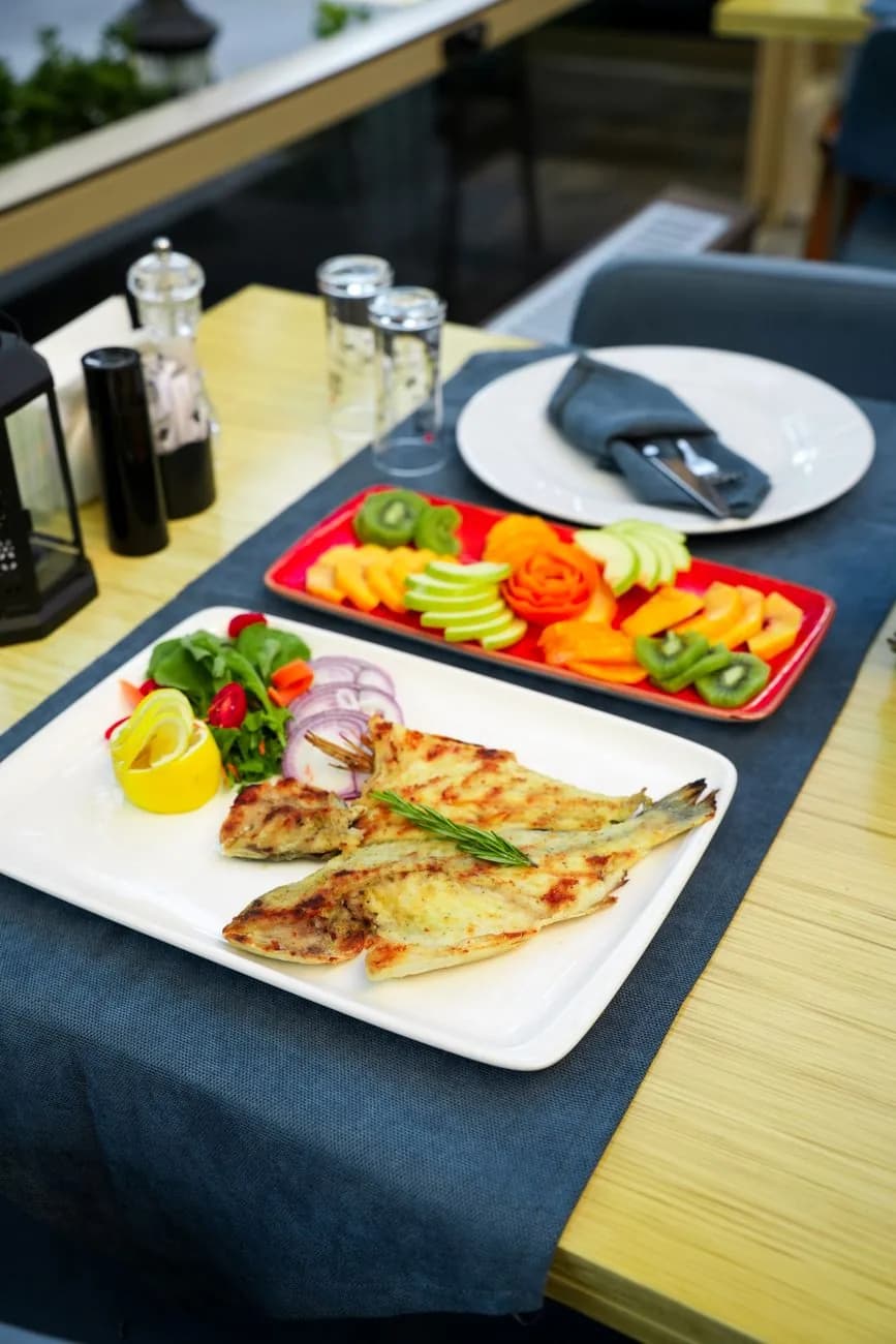 Un poisson entier grillé servi avec citron et salade, comme le lampuki préparé à Malte en fin d'été