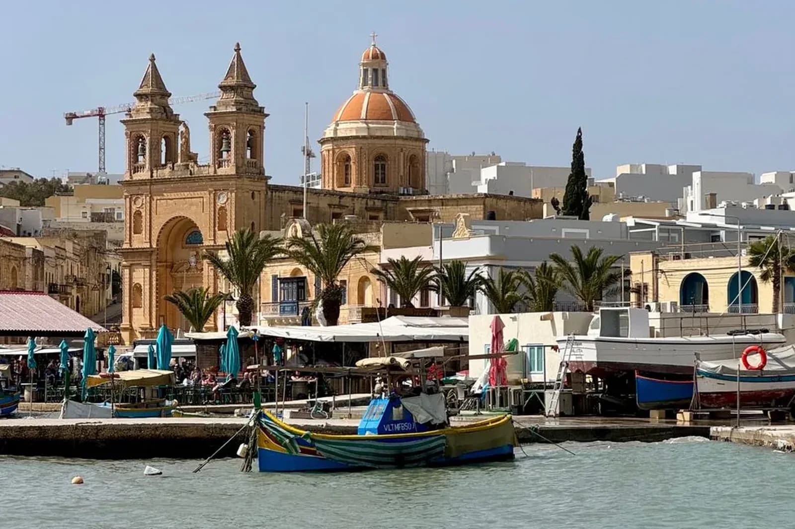 Le port de Marsaxlokk à Malte avec ses luzzu colorés et l'église du village en arrière-plan
