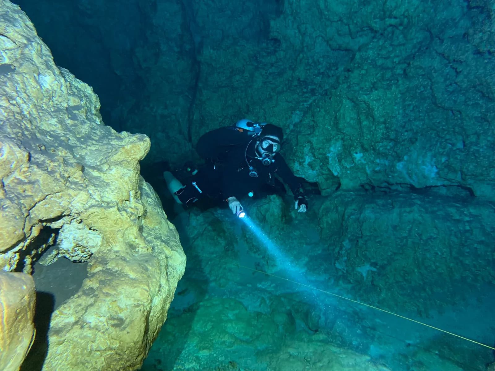 Plongeur éclairant une grotte sous-marine creusée dans le calcaire, comme sur les sites de plongée de Malte et Gozo