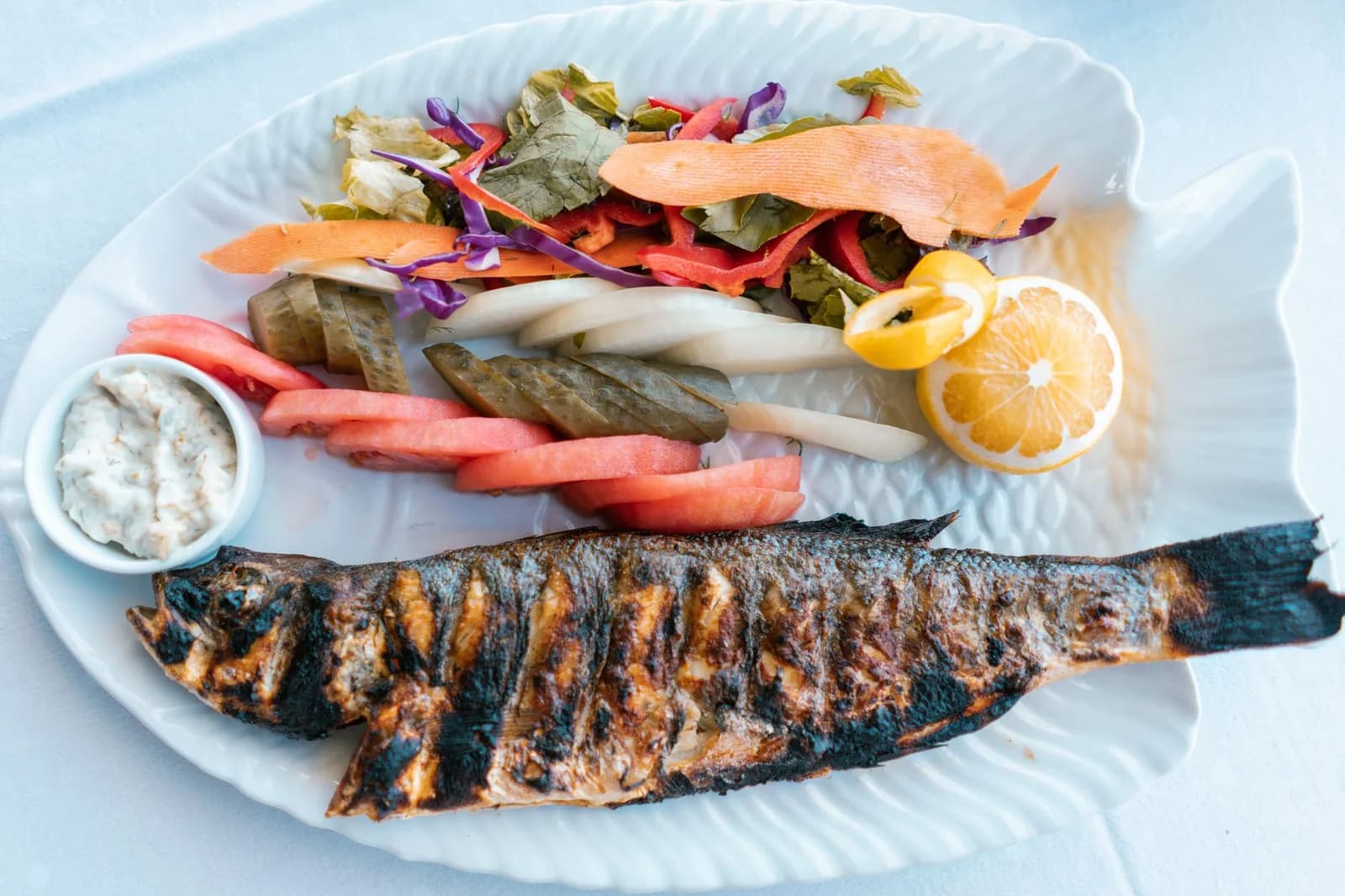 Un poisson entier grillé servi avec salade, citron et sauce, comme dans les restaurants de bord de mer maltais
