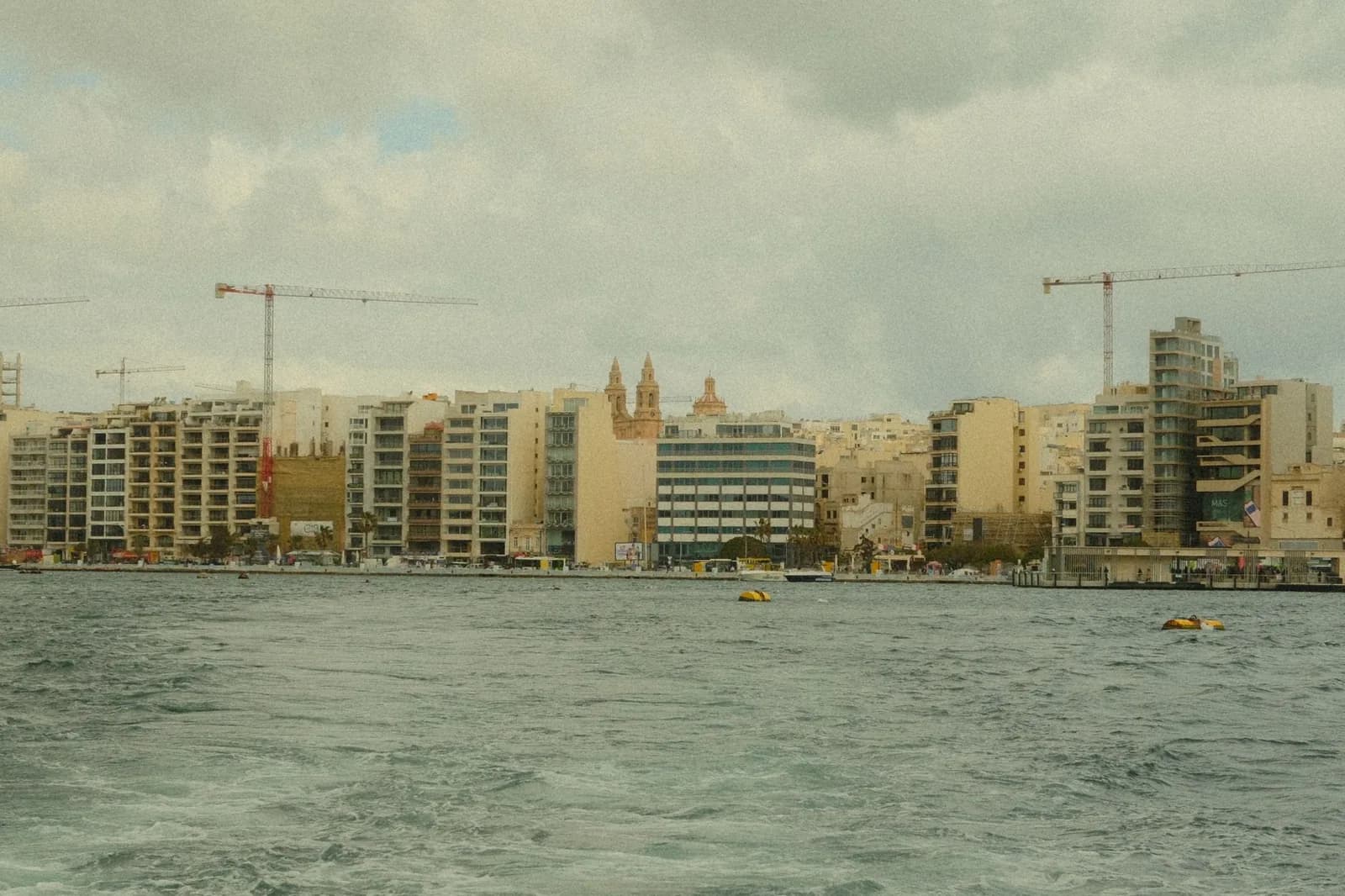 Front de mer de Sliema vu depuis l'autre rive du port, immeubles alignés sous un ciel gris d'hiver