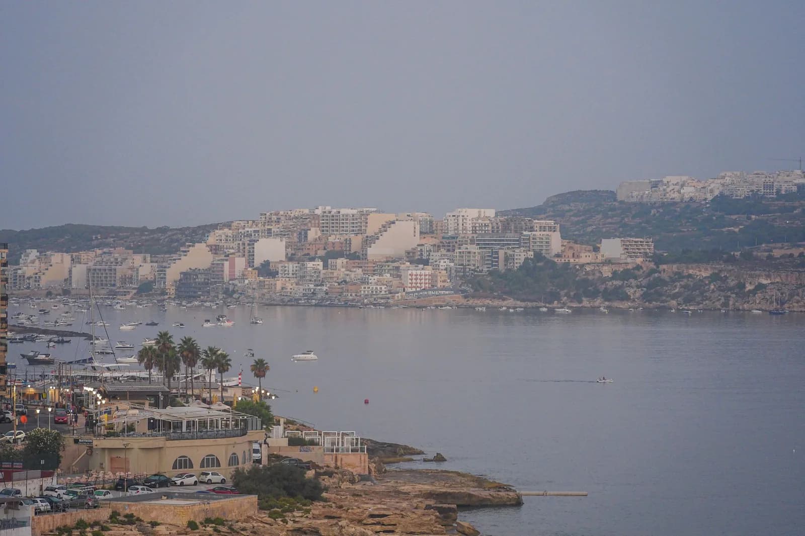 Baie de St Paul vue depuis la pointe de Qawra, Malte, avec palmiers, promenade et immeubles en arrière-plan