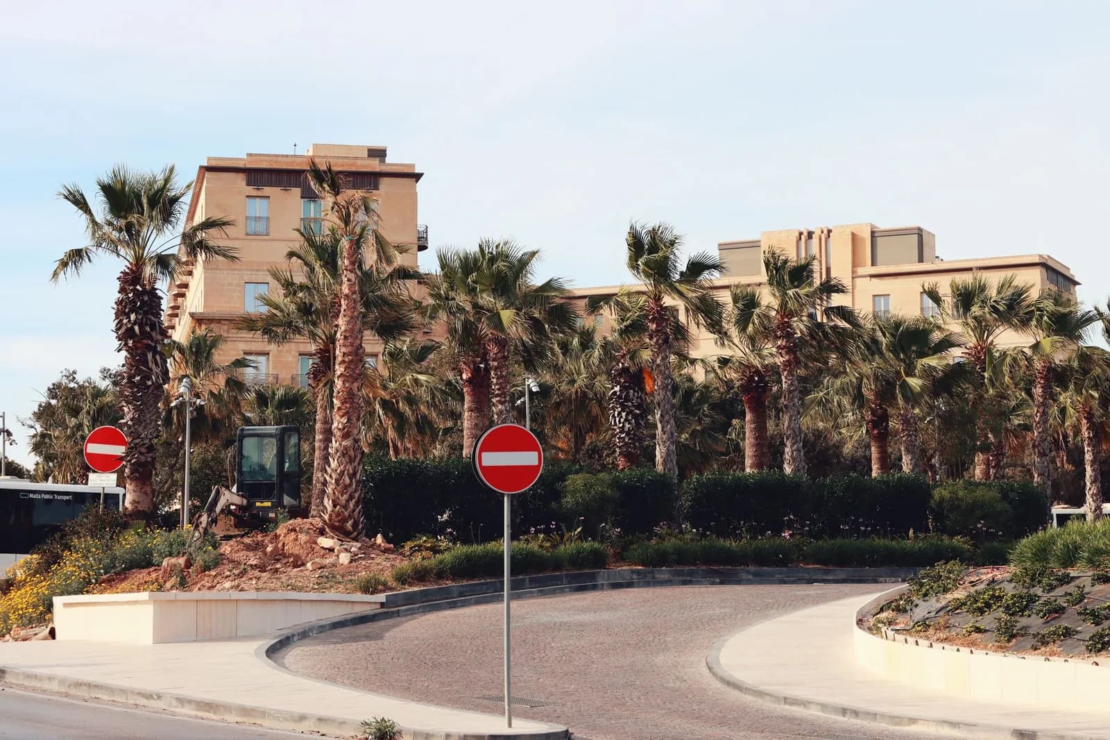 Rond-point bordé de palmiers avec panneaux de sens interdit et bus Malta Public Transport, à Malte