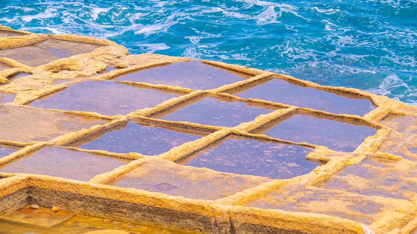 Salines creusées dans la roche au bord de la mer, sur la côte maltaise