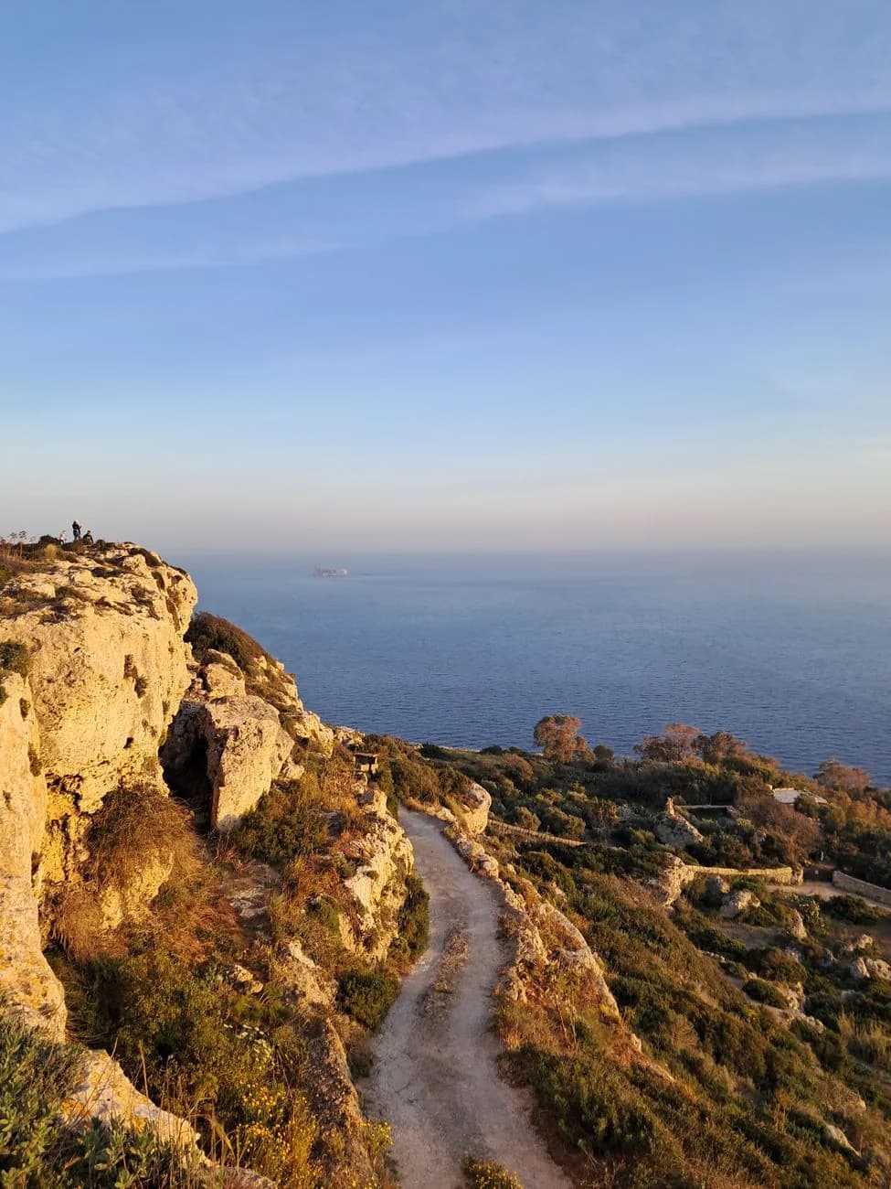 Chemin de terre longeant une falaise calcaire couverte de garrigue au-dessus de la mer, à Malte