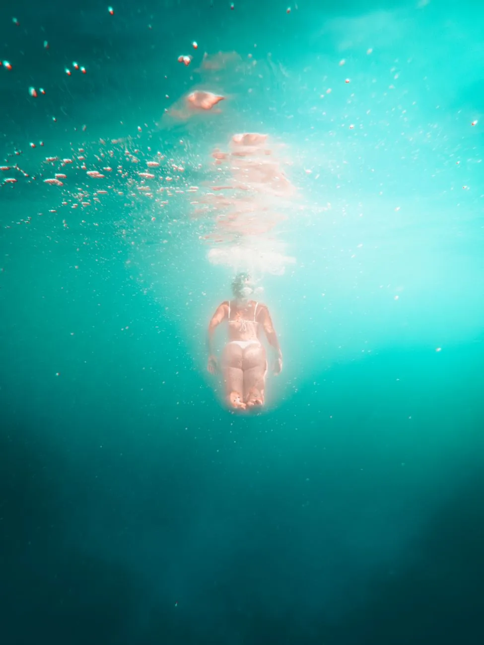 Nageuse en apnée sous la surface dans une eau turquoise très claire, comme en snorkeling à Malte