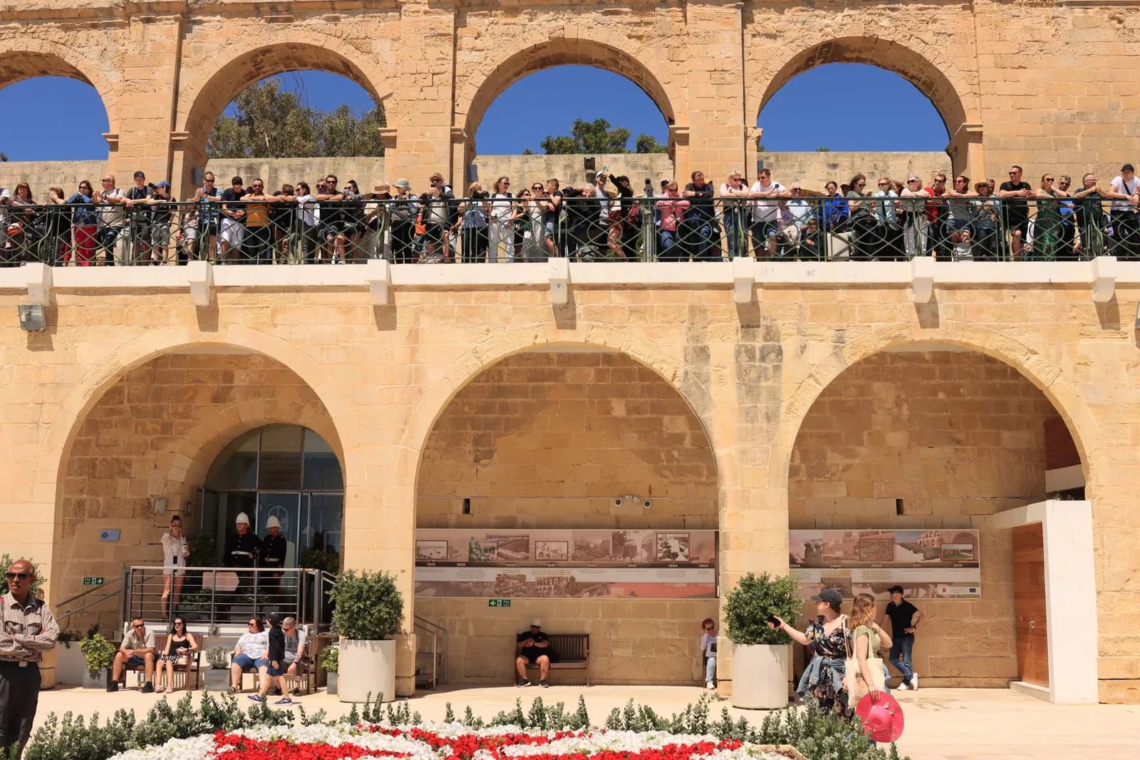 Arcades en pierre des Upper Barrakka Gardens à La Valette, avec des visiteurs accoudés à la terrasse au-dessus